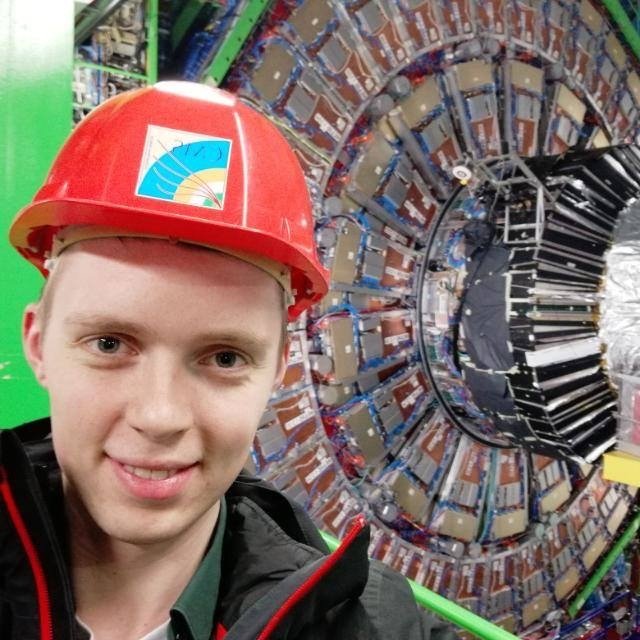 Peter in a red CMS hard hat in front of the CMS detector at CERN during his research internship.